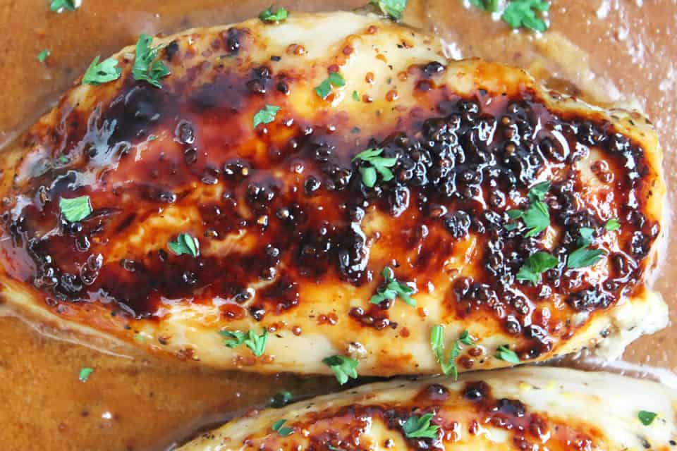 Overhead shot of a honey and mustard chicken breast sitting in sauce.