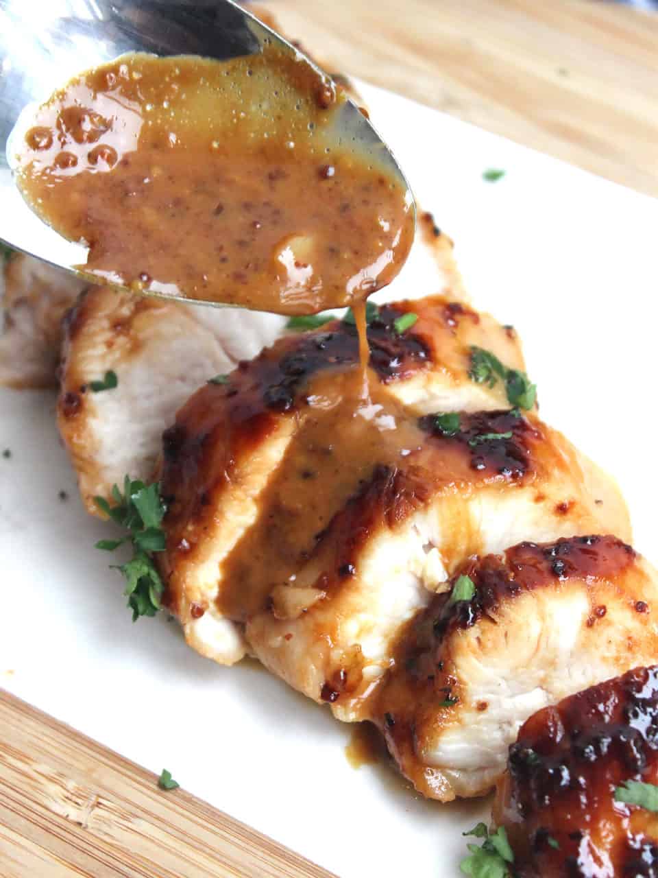 Sauce on a spoon being drizzled over the sliced chicken breast.