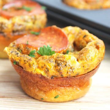 A baked pizza egg muffin garnished with fresh parsley.