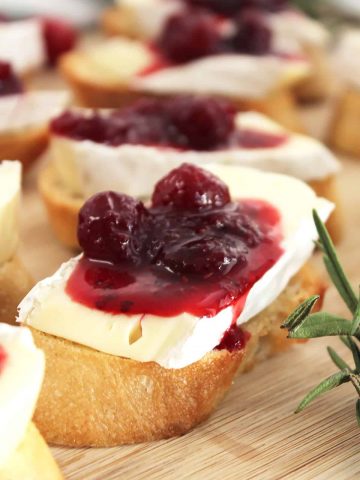 A crostini topped with brie and cranberry sauce.