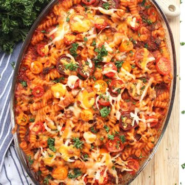 Tomato and beef pasta bake in a glass dish topped with melted cheese.
