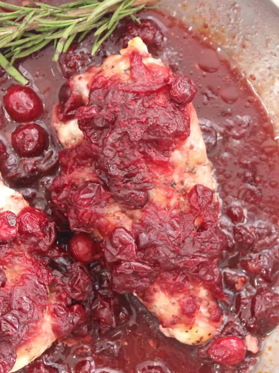 Close up of the cranberry sauce on top of a baked chicken breast.