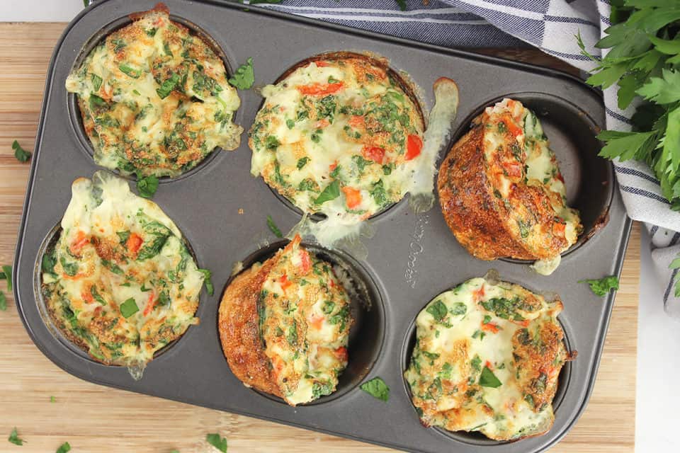 Six egg ehite bites in a muffin tin garnished with fresh parsley.