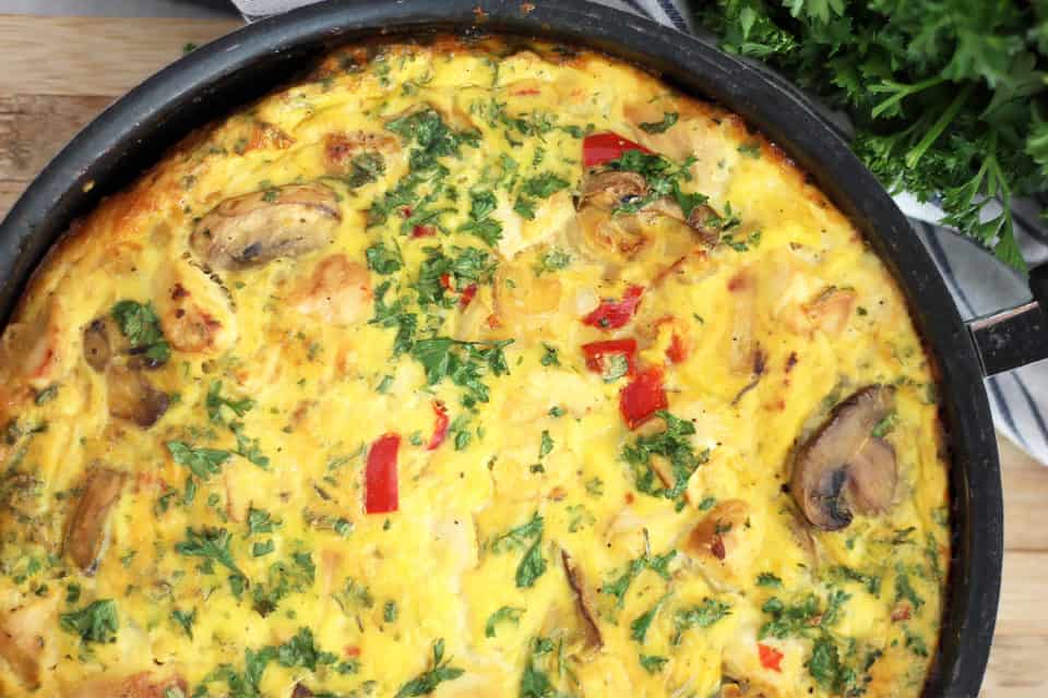 Close up of the chicken and vegetable frittata in a black skillet.