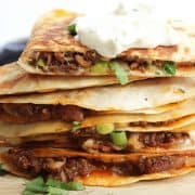 A stack of quesadillas topped with sour cream.