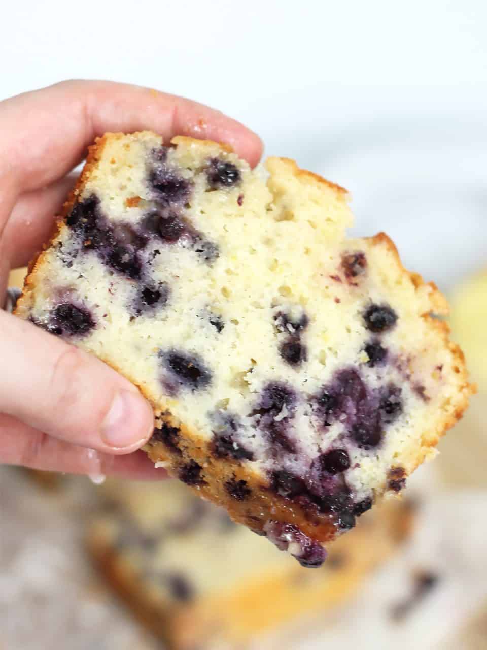 A slice of lemon blueberry pound cake being held.
