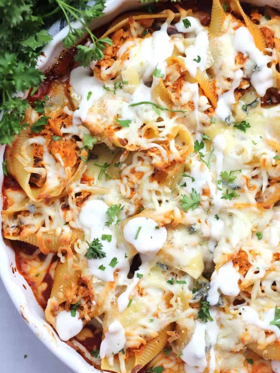 Buffalo stuffed chicken shells with ranch dressing and fresh parsley.
