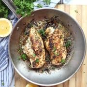 Two lemon oregano chicken breasts cooked in a skillet.