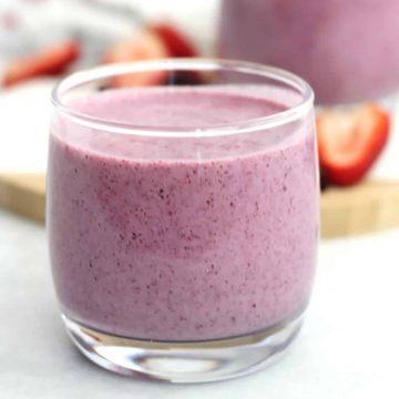 A blueberry strawberry smoothie in a small glass.