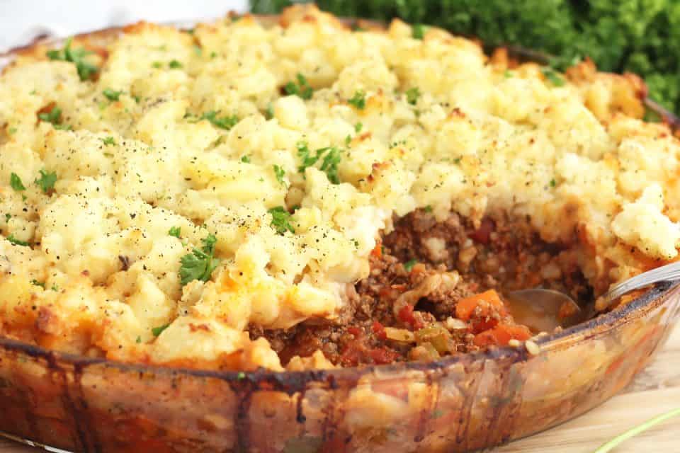 Side view of the beef and potato casserole in a glass baking dish.