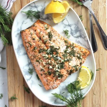 Honey lemon salmon fillet served on a plate with lemon wedges and fresh dill.
