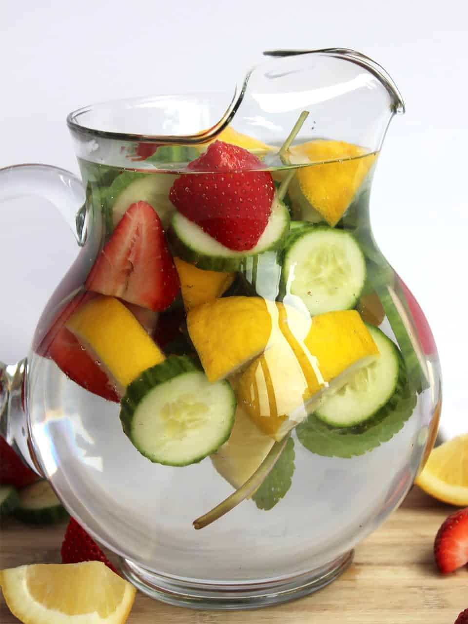 Strawberry infused water with lemon, cucumber and mint in a glass jug.
