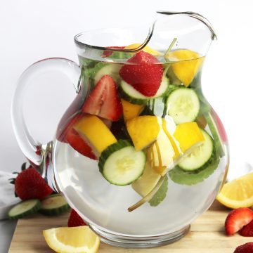 A jug of strawberry infused water with fresh fruits and mint.