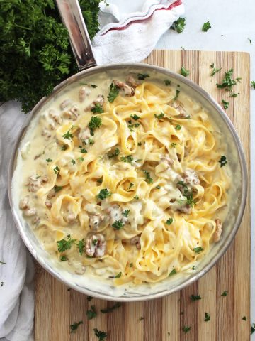 Pasta tossed in blue cheese sauce in a silver skillet and garnished with parsley.