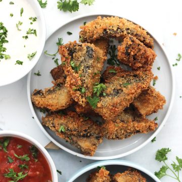 Fried portobello mushrooms on a small serving plate garnished with fresh parsley.