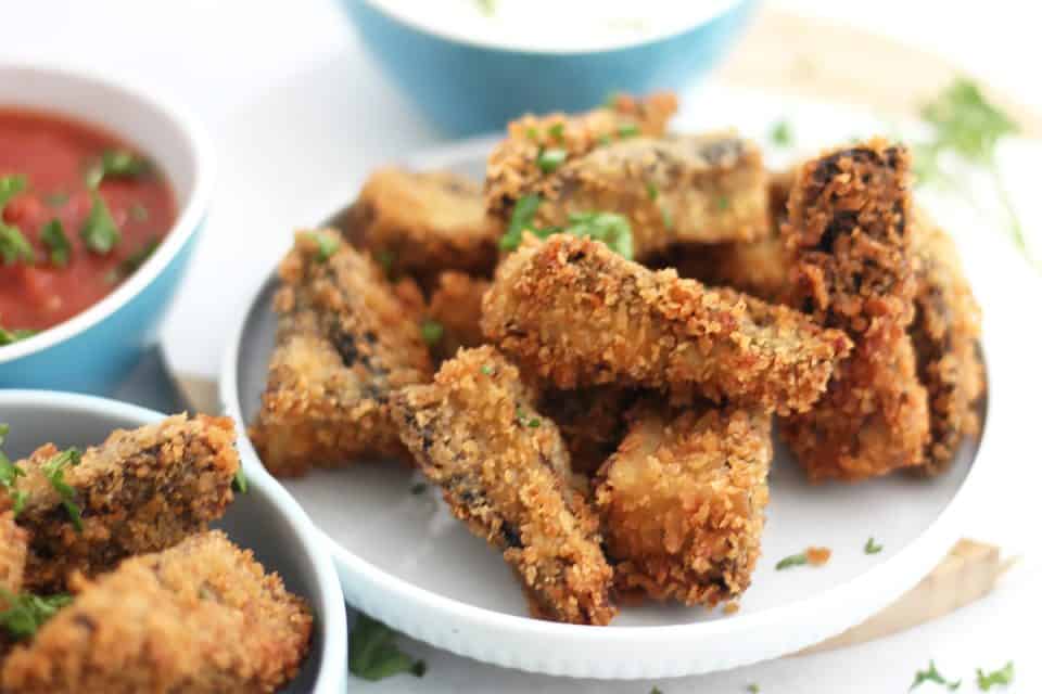 Fried mushrooms on a small serving plate next to dips.
