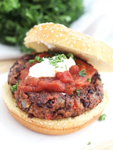A spicy black bean burger topped with salsa, sour cream and parsley.