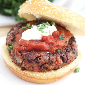 A spicy bean burger in a bun topped with sour cream and salsa.