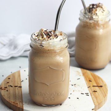 Chocolate coffee milkshake in two mason jars topped with whipped cream.