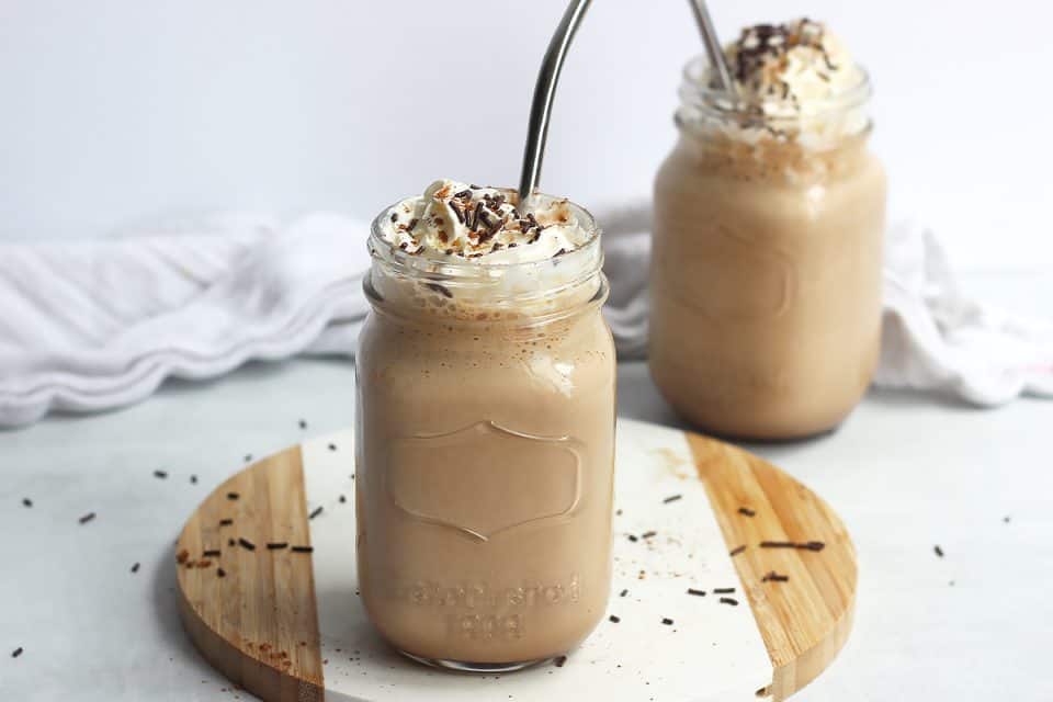Two mason jars filled with chocolate coffee milkshake with metal straws.