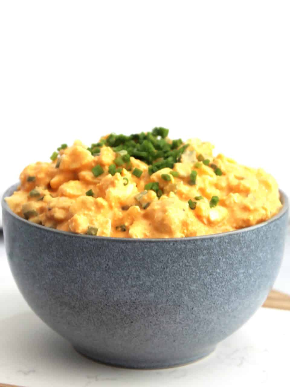 Buffalo egg salad in a bowl with fresh chives on top.