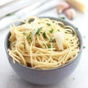 Garlic spaghetti in a blue bowl topped with shaved parmesan.
