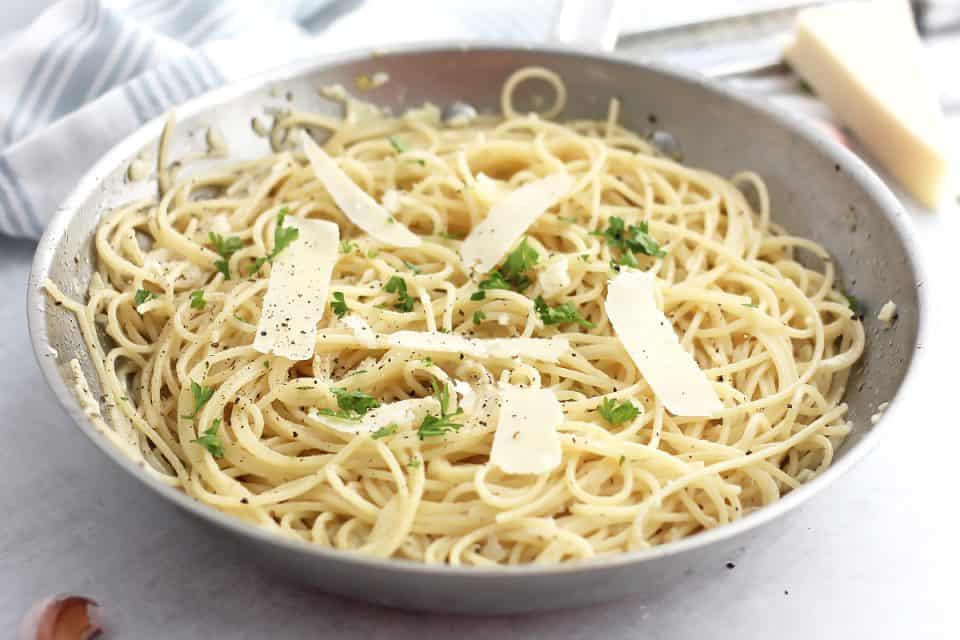 Garlic parmesan spaghetti in a skillet topped with fresh parsley.