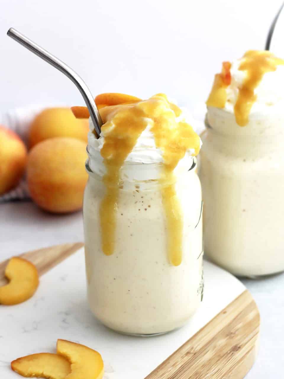 Two peach milkshakes in glass jars topped with peach puree.