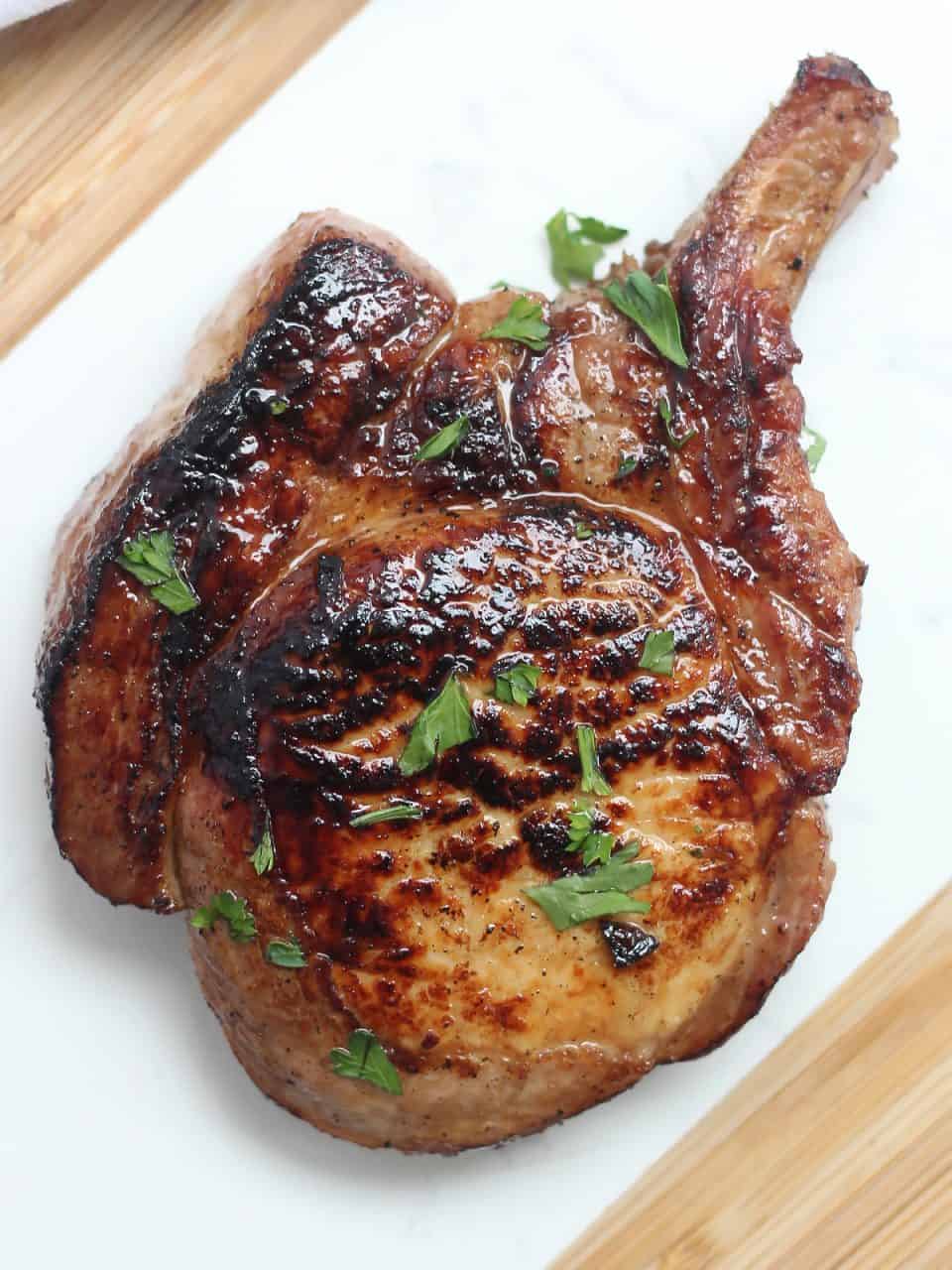 Overhead shot of a cooked pork chop with fresh herbs.