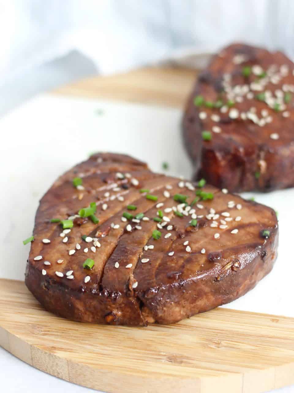 Two air fryer tuna steaks garnished with sesame seed and chives.