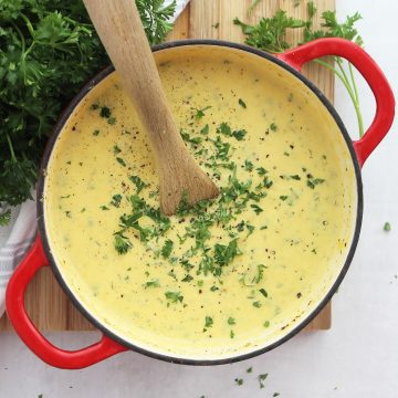 Creamy celery and carrot soup in a red Dutch oven with a wooden spoon.
