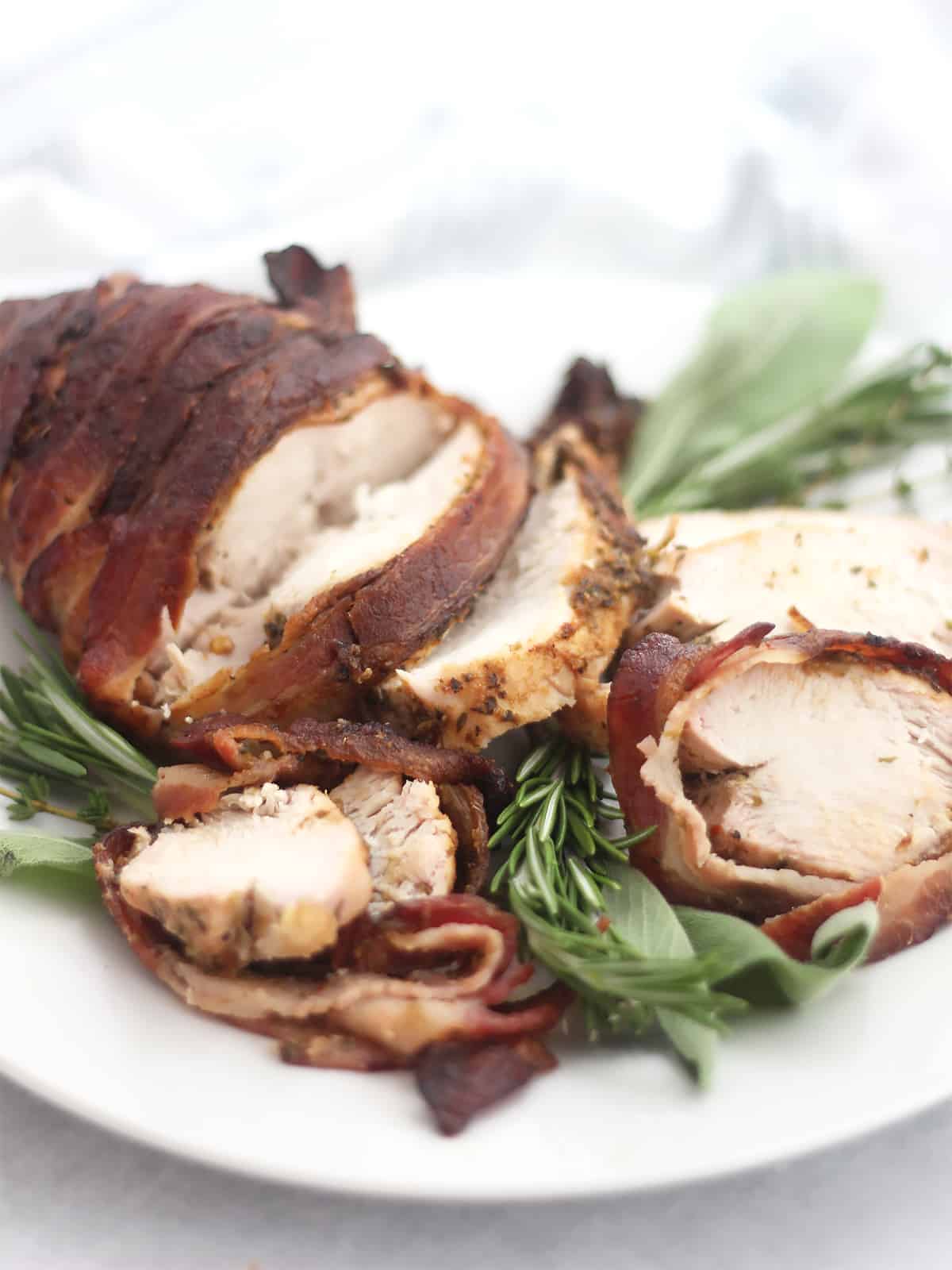 Air fryer bacon wrapped turkey breast carved on a plate.