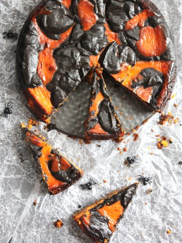 A chocolate orange halloween cheesecake with two slices cut out of it.