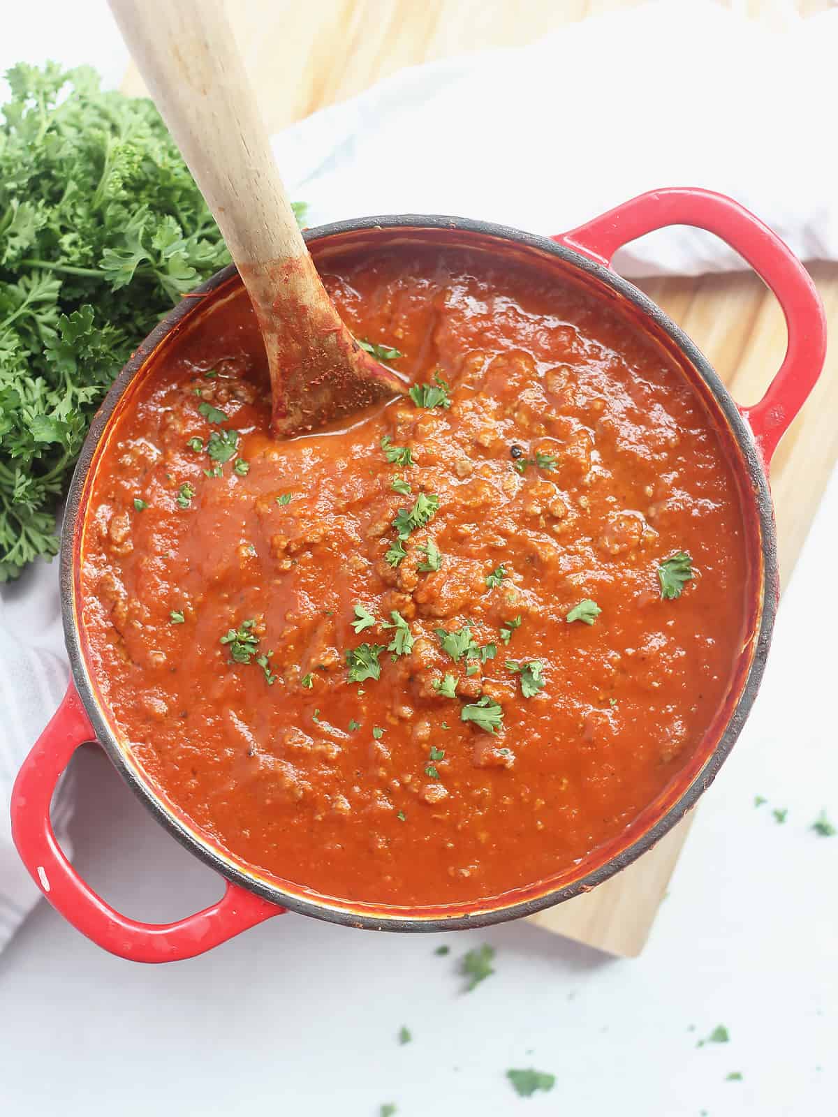 Ground beef and tomato soup in a red Dutch oven with a wooden spoon.