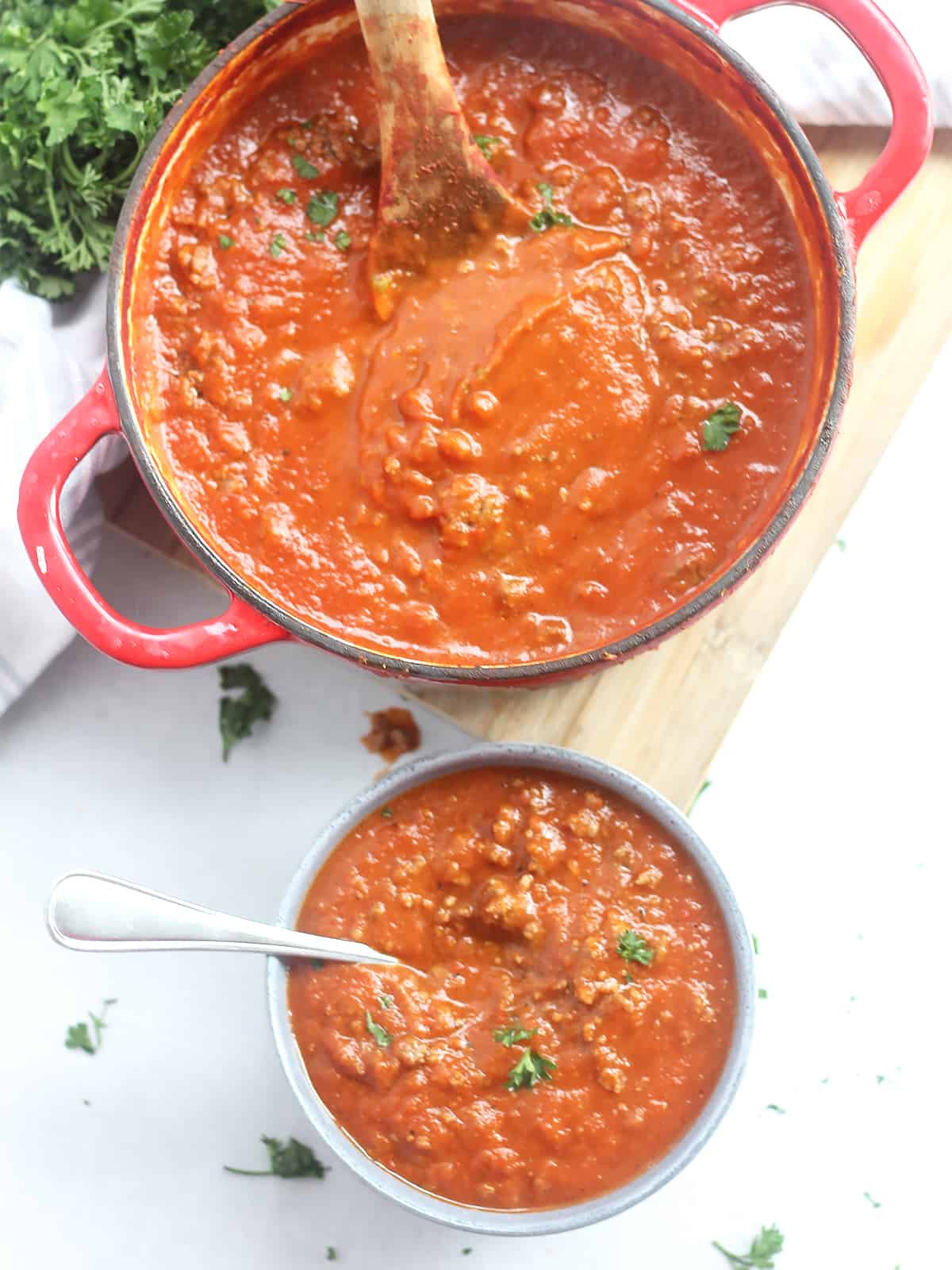 Overhead shot of the beef and tomato soup in a dutch oven and some served into a bowl.