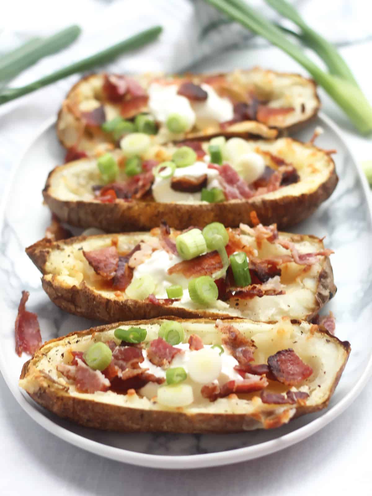 Four air fryer potato skins with toppings.