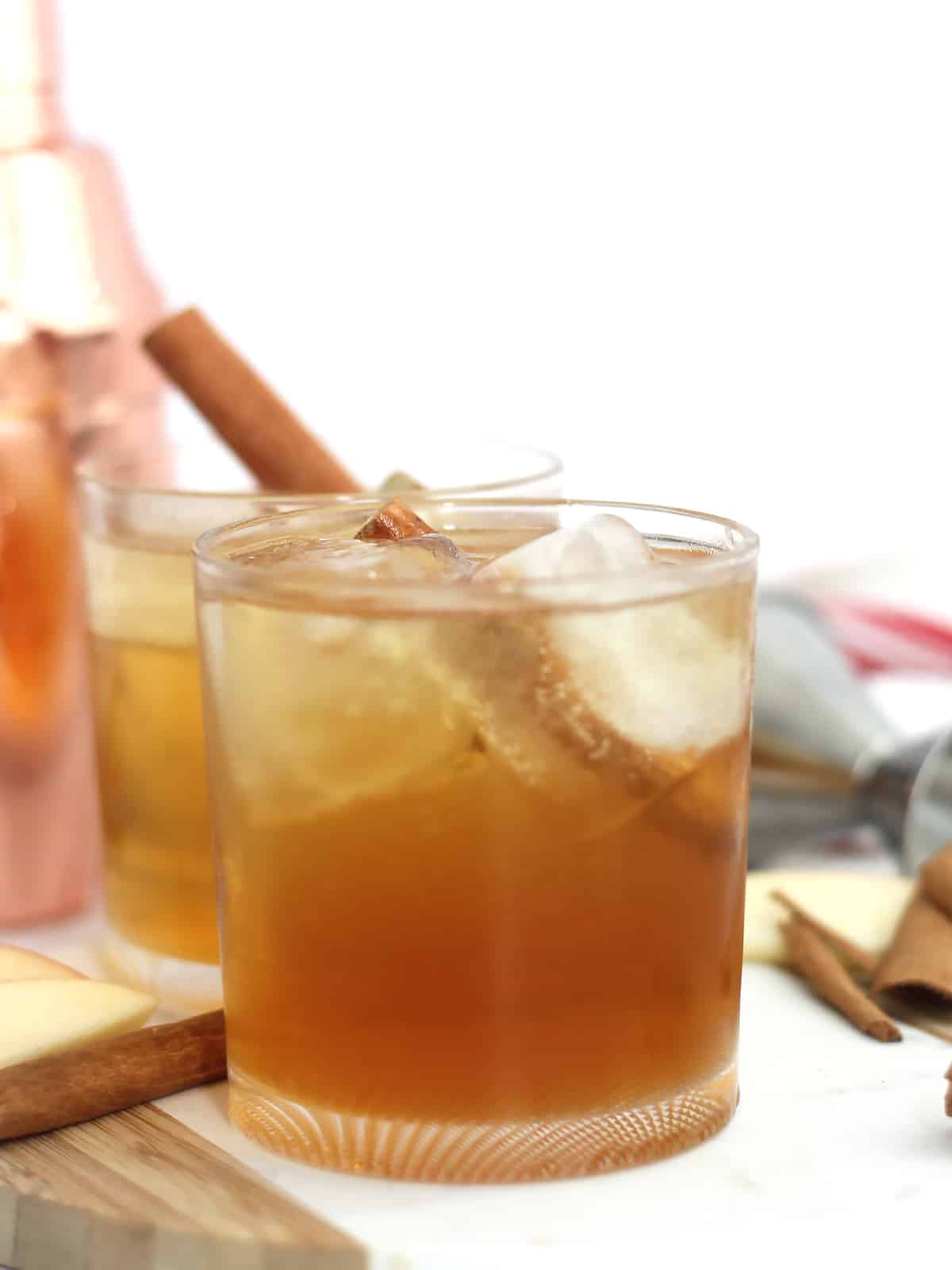 A cocktail with large ice cubes and a cinnamon stick.