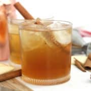 Two fireball whiskey cocktails with ice and a cinnamon stick.