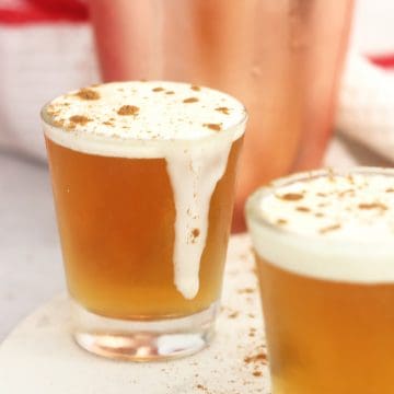 A cinnamon Fireball shot with cream running down the side of the glass.