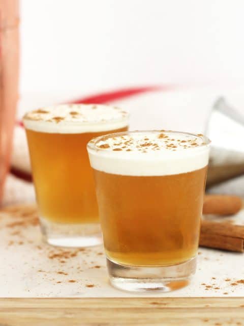 Two whiskey shots in glasses sprinkled with ground cinnamon.
