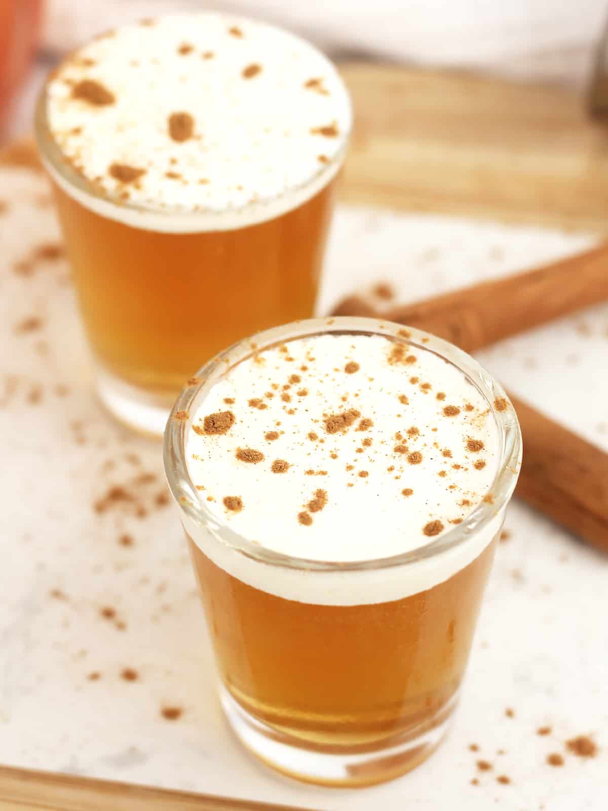 Two whiskey shots topped with cream and cinnamon.