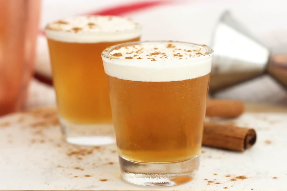 Two Fireball whiskey shots topped with cream and ground cinnamon.