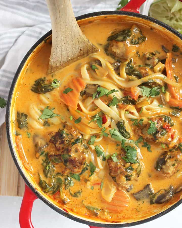 A wooden spoon in a pot of Thai meatball soup.