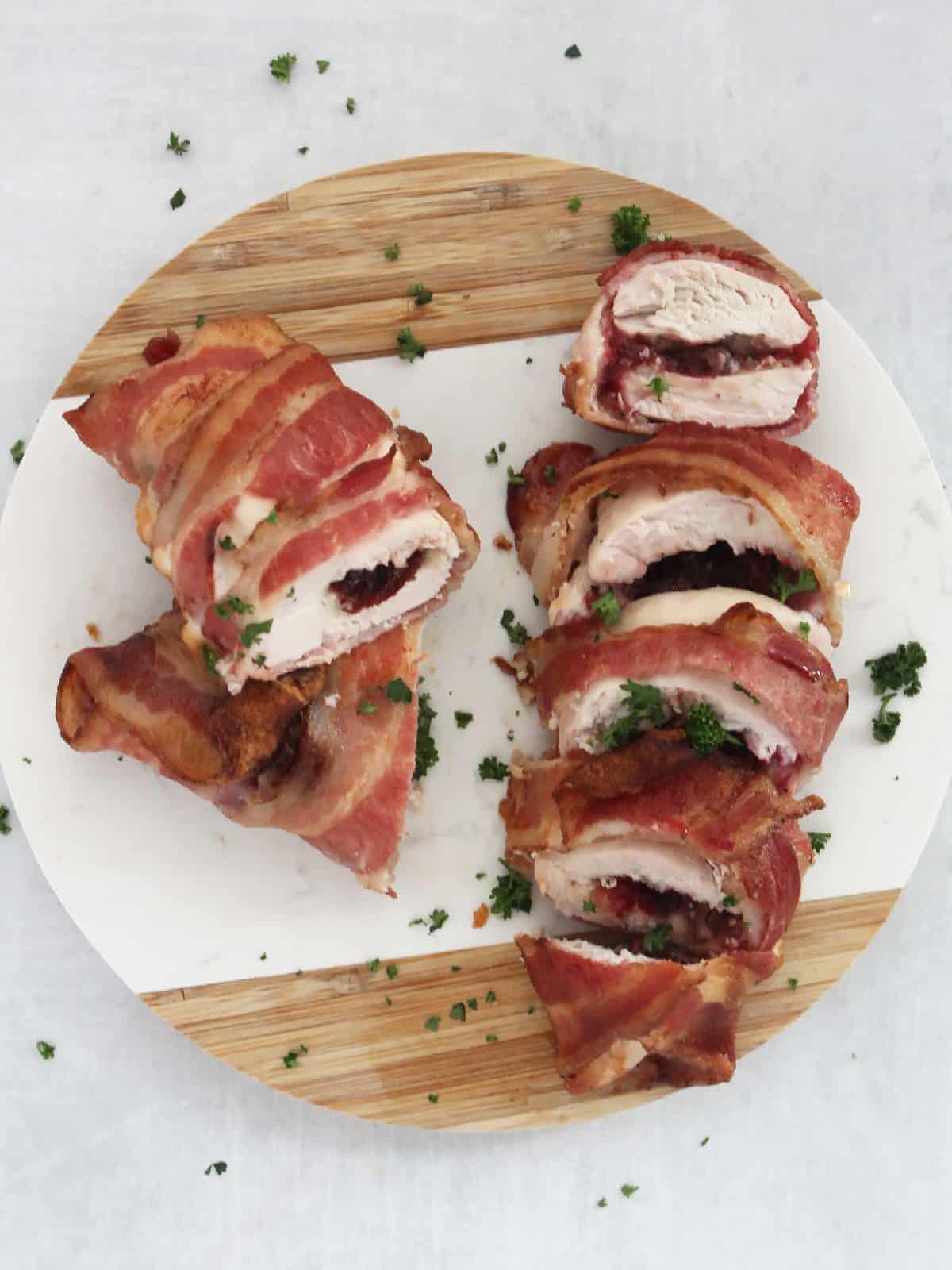 Overhead shot of two cranberry brie stuffed chicken breasts wrapped in bacon.