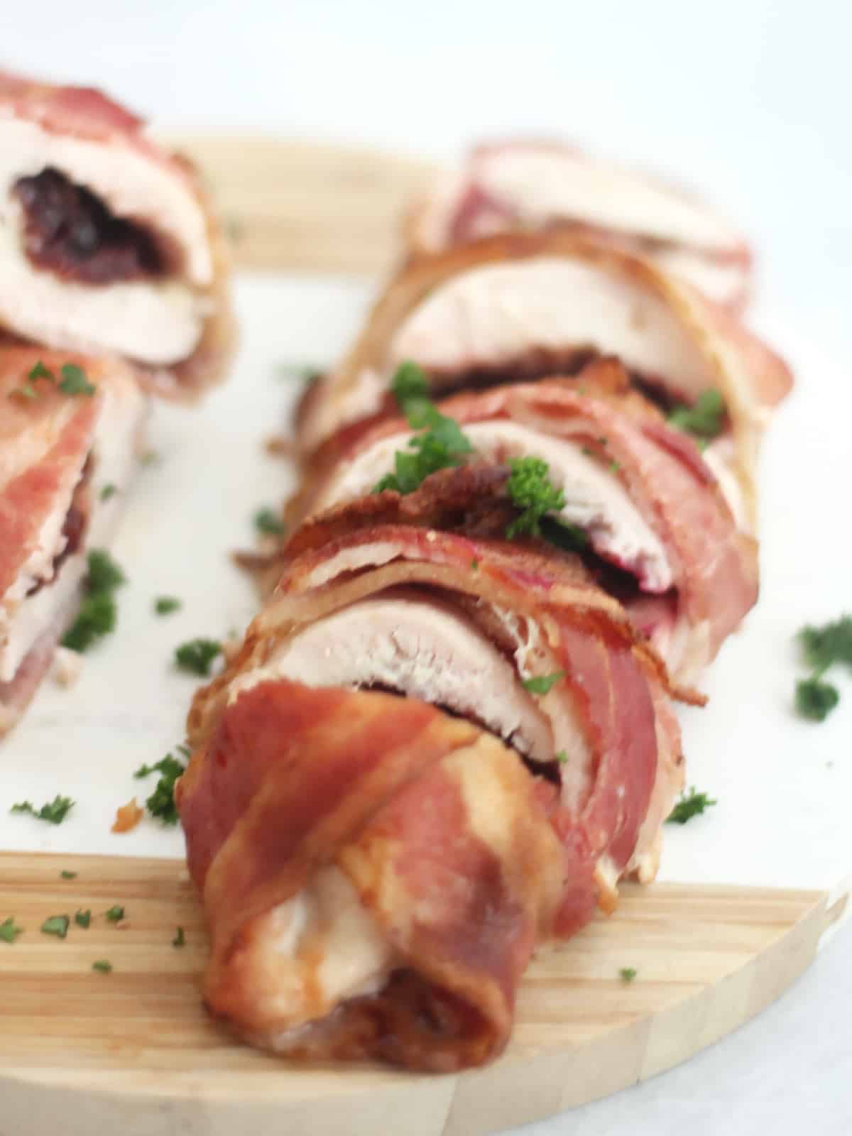 Bacon wrapped sliced chicken breast on a chopping board.