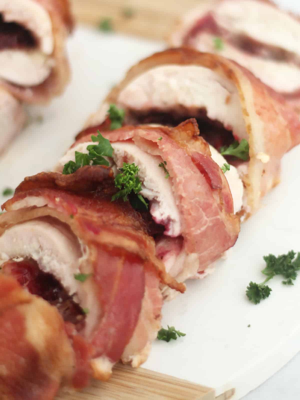 Sliced chicken breast wrapped n bacon and garnished with parsely.