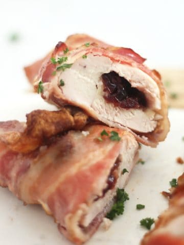 A stuffed chicken breast wrapped in bacon cut in half to show the brie and cranberry stuffing.