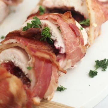 Close up of sliced bacon wrapped chicken stuffed with brie and cranberry sauce.