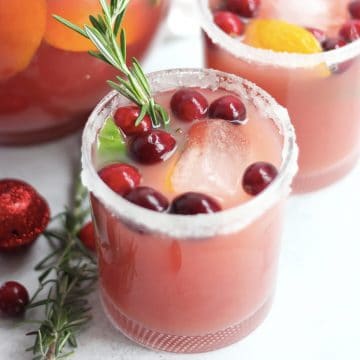 A cranberry orange drink in a glass with a sugared rim.