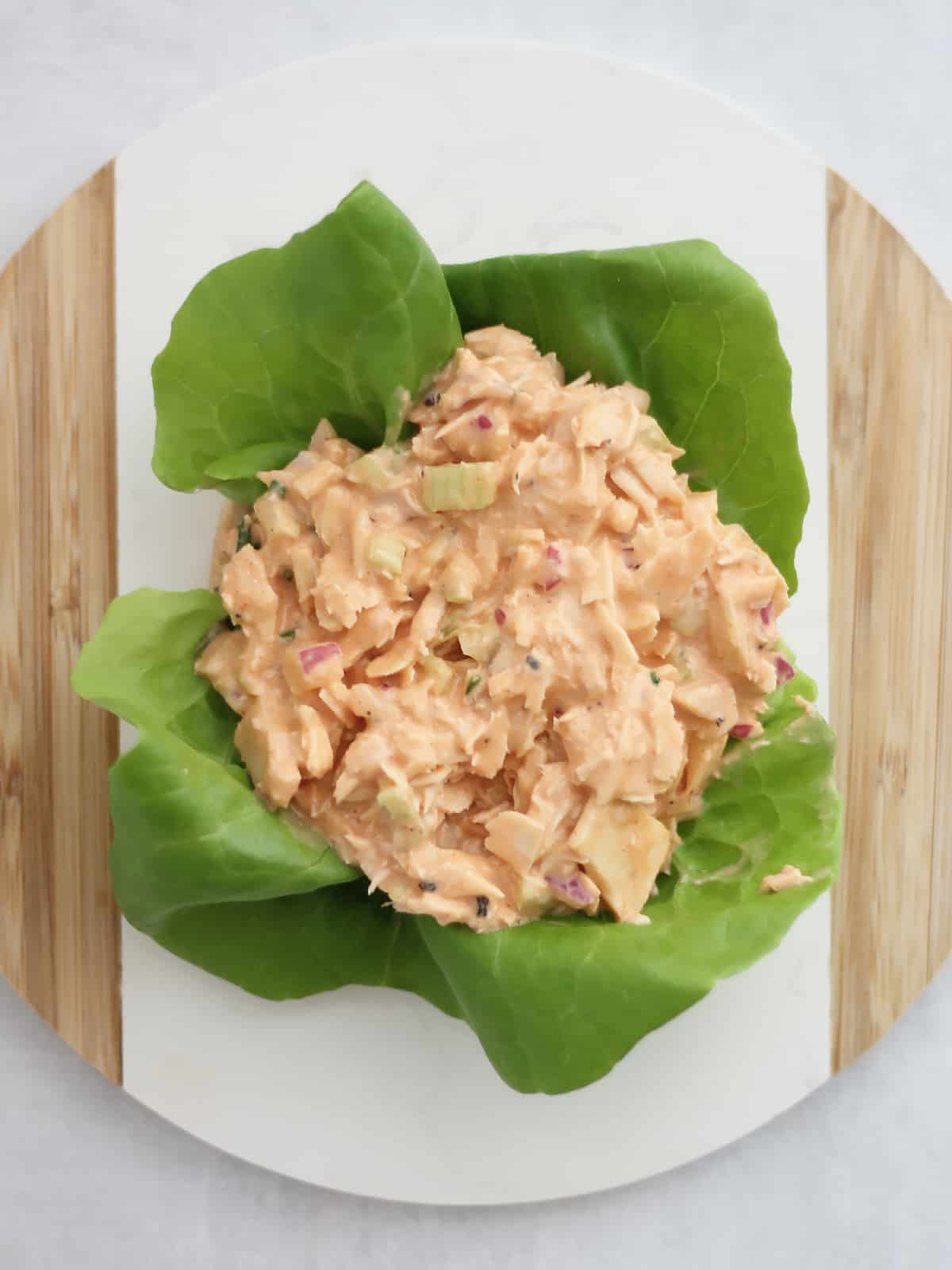 Buffalo tuna salad on top of a slice of bread and lettuce leaves.